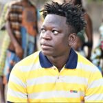 Home Portrait of a man with a striped shirt in Atakpamé, Togo, showcasing local culture.