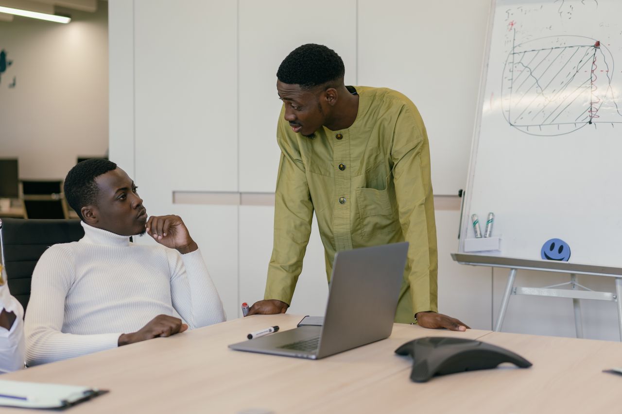 our-services-01 Two men in a business meeting discussing strategies in a modern office setting.